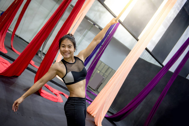 Young Asian gymnast woman doing anti-gravity yoga or yoga fly in aerial gym - Foto, Bild