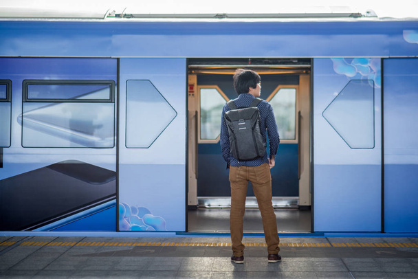 Ein junger asiatischer Mann steht vor der U-Bahn auf dem Bahnsteig in der Stadt. urbanes Lifestyle-Konzept - Foto, Bild