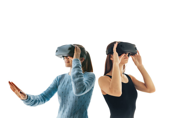 白い背景の上の仮想現実の眼鏡の 2 つの若い女の子.近代的な技術や未来の技術コンセプト。Vr メガネ - 写真・画像