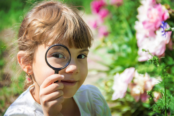 The child is looking in a magnifying glass. Increase. selective focus. - Foto, Imagem