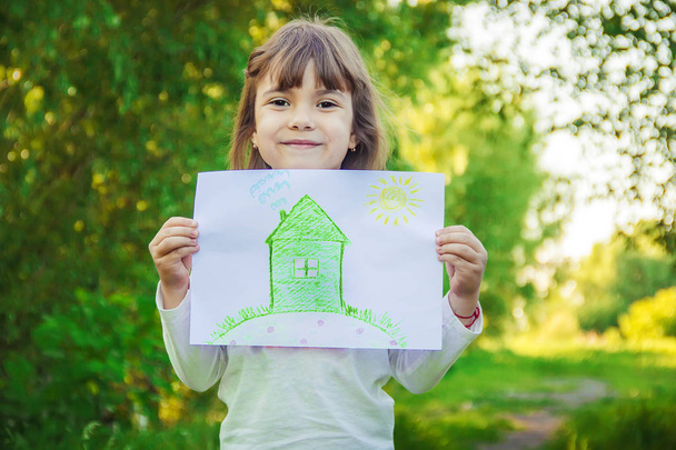 Dibujo de un invernadero en manos de un niño. Enfoque selectivo
.  - Foto, Imagen