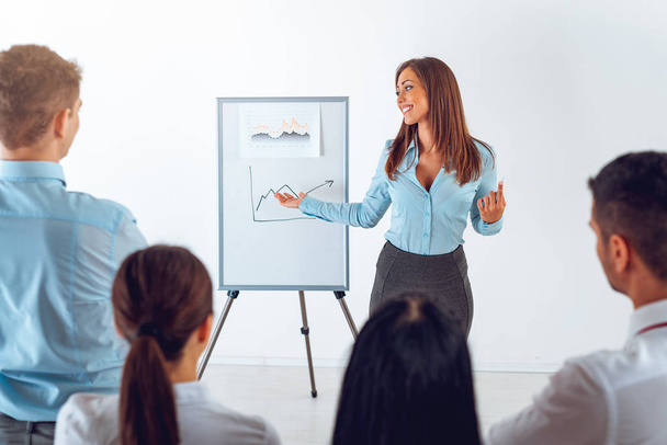 Young businesswoman standing in front of flip chart and having presentation. - Photo, Image