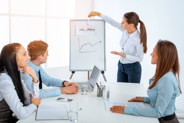 Young businesswoman standing in front of flip chart and having presentation - Foto, Bild