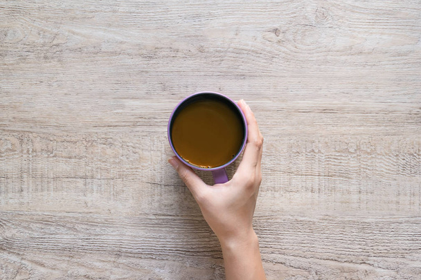 Чашка кофе в руке женщин на фоне текстуры дерева
. - Фото, изображение