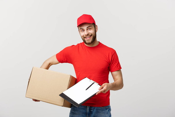 Delivery Concept: Young handsome delivery man with paper boxes giving you a document to sign - Photo, Image