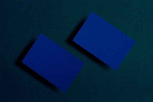 Mock up van twee horizontale blauwe visitekaartjes bij donker blauw geweven papier achtergrond. Mock-up sjabloon voor branding identiteit. Voor grafisch ontwerpers presentaties en portefeuilles - Foto, afbeelding