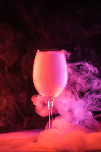 wine glass with mystical pink smoke on black background - Foto, immagini