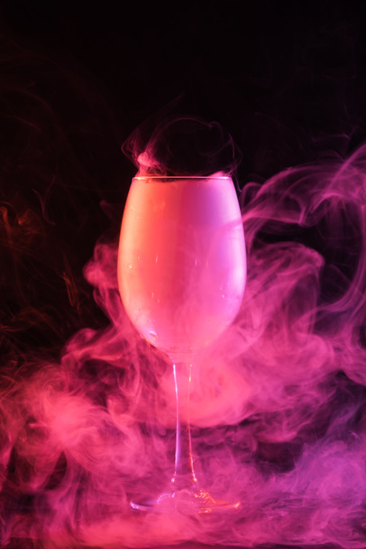 glass with pink spiritual smoke on black background - Fotó, kép