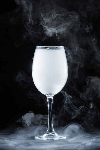 wineglass with white smoke on black background - Foto, afbeelding