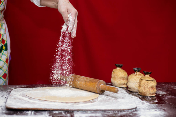 Femme cuisinier saupoudrer de farine sur la planche à découper. Cuisiner. Faire du pain sur la table de cuisine. Concept de processus de cuisson
 - Photo, image