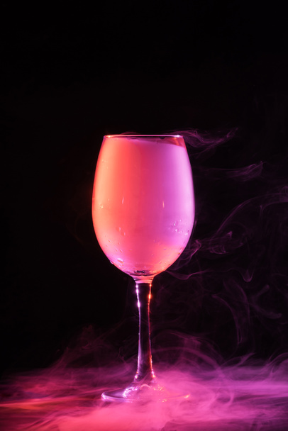 wineglass with pink smoke on black background - Foto, Bild
