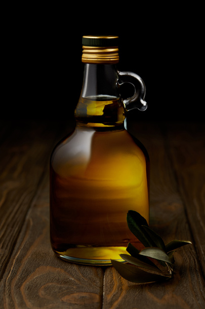 bouteille d'huile d'olive aromatique avec branche sur surface en bois
 - Photo, image