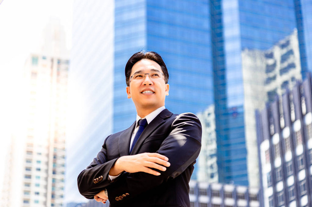 Portrait confidence and determined handsome executive man. Charming handsome businessman is crossing arms and look confident. Handsome guy get successful of business. metropolis background, copy space - Photo, Image