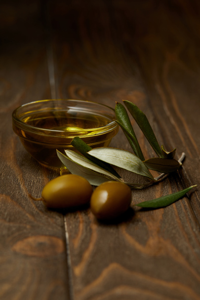 gros plan de l'huile d'olive avec branche d'olives sur la surface en bois
 - Photo, image