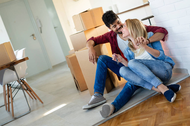 Young happy couple in love moving in new home and unpacking boxes - Фото, изображение