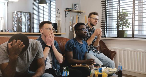 Multi ethnic men disappointed watching sports game. 4K Passionate geeky fans get emotional and sad. Loss and failure. - Foto, Imagen