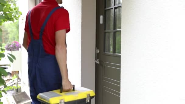 Arbeiter mit Werkzeugkiste läuft zu einem Kundenhaus und klingelt an der Tür - Filmmaterial, Video