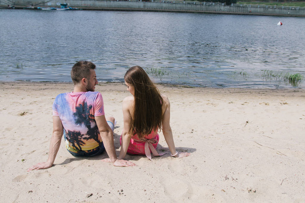 junges Paar, das sich am Ufer des Flusses umarmt und anlächelt. Wandern am Sandstrand - Foto, Bild