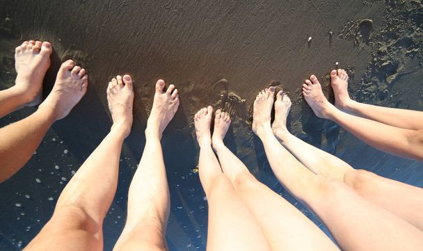 Босоногие ноги молодой семьи из пяти человек с длинными ногами на берегу моря летом
 - Фото, изображение