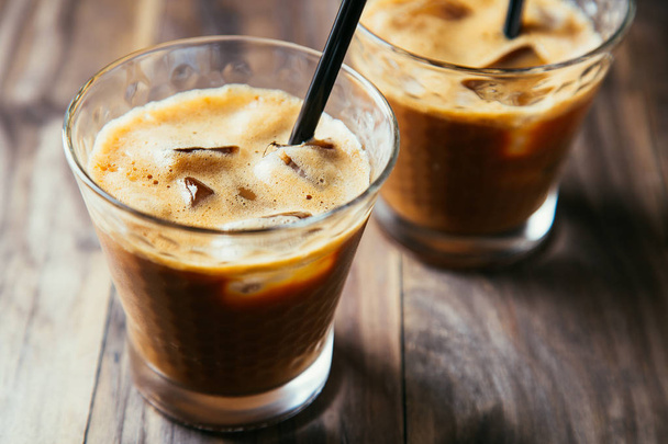 Two glasses of iced coffee latte with straws on a rustic wooden table - Photo, Image