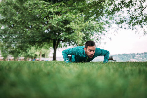 Young man doing push ups in the park. - 写真・画像