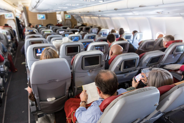 Interiér z velké komerční letadla s cestujícími na svých sedadlech během letu. - Fotografie, Obrázek