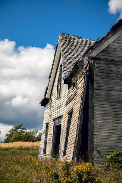 Zijaanzicht van een vervallen huis in landelijke New Brunswick, Canada. Zijaanzicht tonen de voorgevel aanhankelijk van de rest van de structuur. - Foto, afbeelding