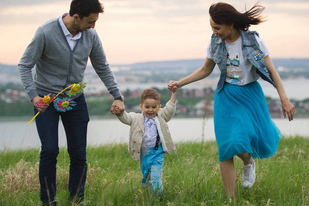 Os pais com um bebê se divertem e andam ao ar livre
 - Foto, Imagem