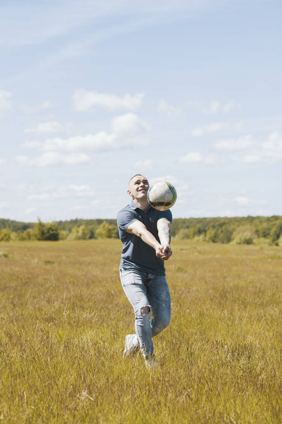 Young man playing volleyball in a summer field - Photo, Image