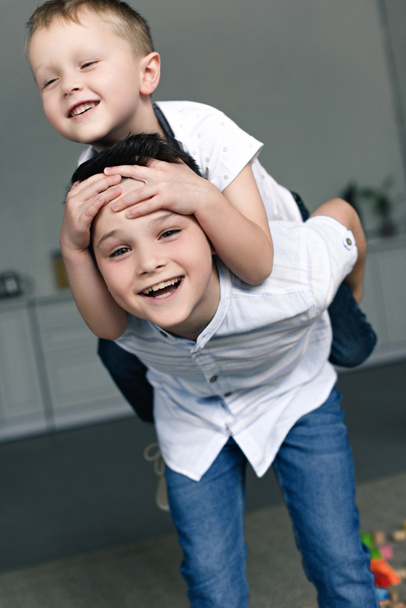 portret szczęśliwy braci piggybacking razem w domu - Zdjęcie, obraz