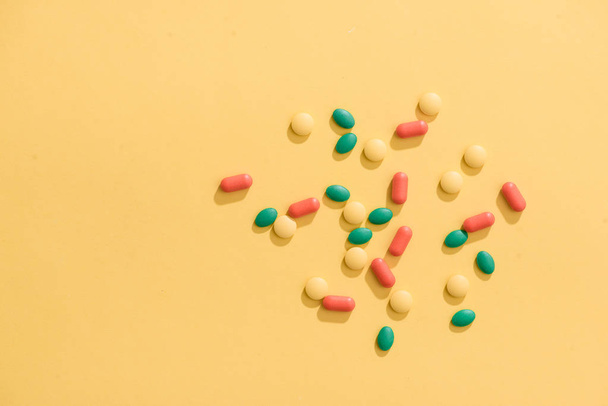 Colorful pills on yellow background with copy space - Foto, Bild