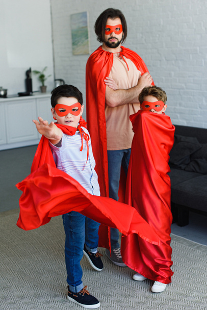 homem e filhos bonitos em trajes de super-herói vermelho em casa
 - Foto, Imagem