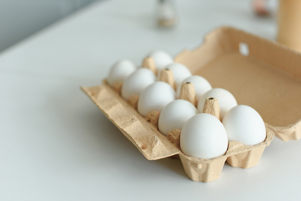 Nahaufnahme roher Hühnereier in Schachtel auf Tischplatte in der Küche - Foto, Bild