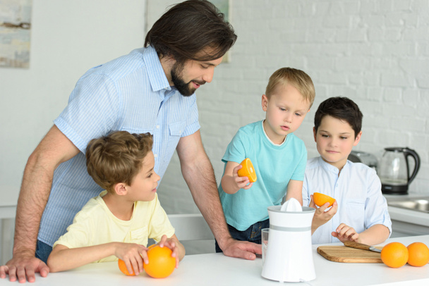portrait of family making fresh orange juice in kitchen at home - Foto, Imagem