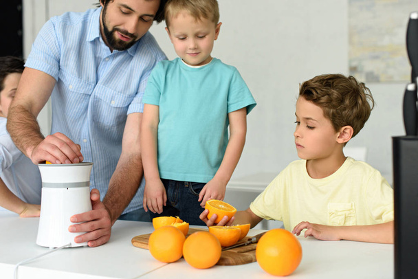 partial view of family making fresh orange juice together in kitchen at home - Photo, Image
