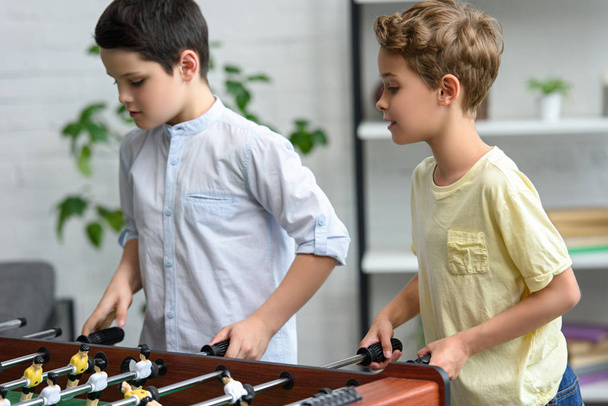 focused little boys playing table football together at home - Foto, Bild
