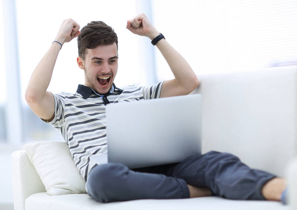 homem feliz com laptop sentado no sofá
 - Foto, Imagem