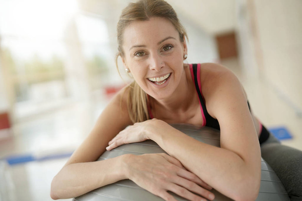 Mujer en el gimnasio relajándose en la pelota de fitness
 - Foto, imagen