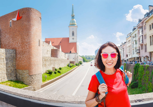 Reisende Frau mit Rucksack lächelt vor dem Hintergrund der St. Martin Kathedrale in Bratislava, Slowakei - Foto, Bild