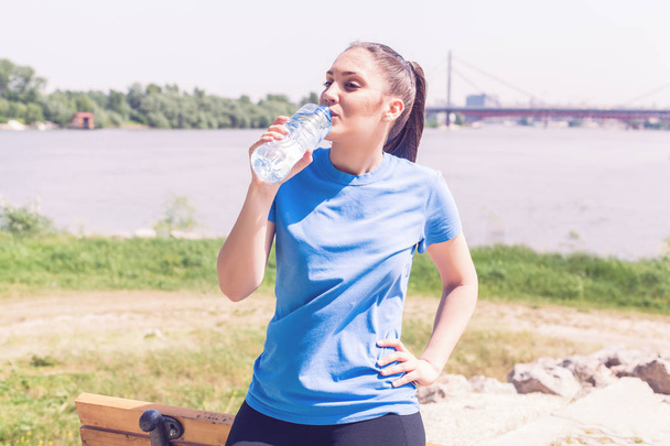  Fitness girl refresh, sporty woman drinking water after exercising outdoor - Photo, Image
