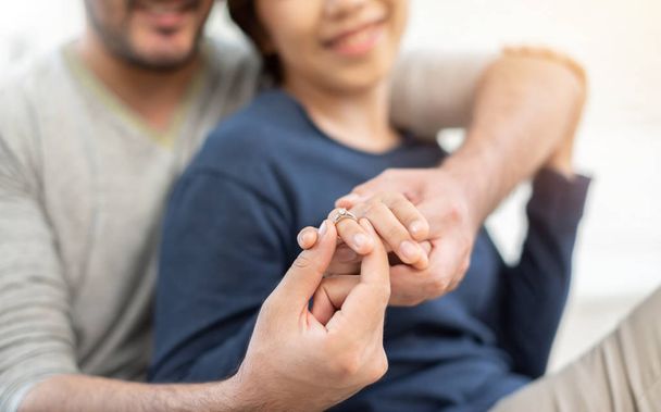 Young man giving engagement ring to his beautiful girlfriend in new moving house day. - 写真・画像