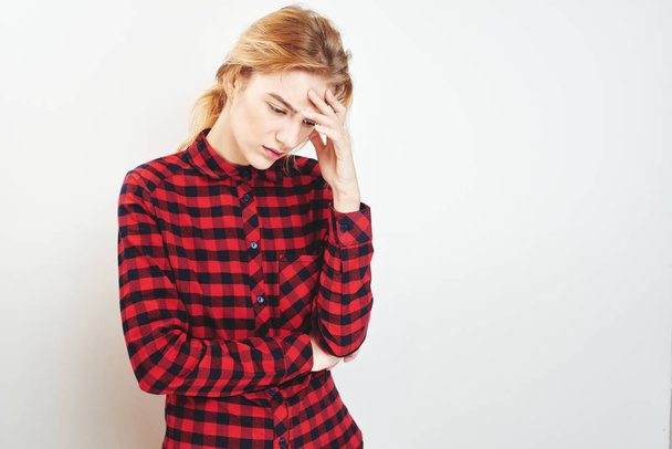 Portrait of young thoughtful woman in checkered shirt touching forehead isolated on white background, concept of memory problems  - Fotoğraf, Görsel