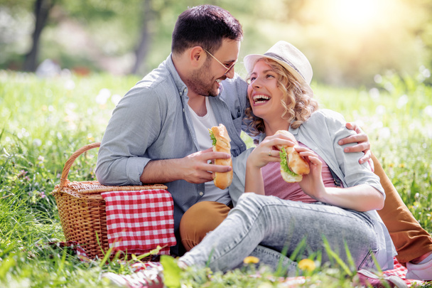 Jeune couple amoureux manger des sandwichs et profiter dans le parc
. - Photo, image