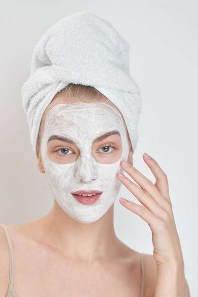 smiling  woman with towel on head applying mask on face , beauty treatment concept  - Photo, Image