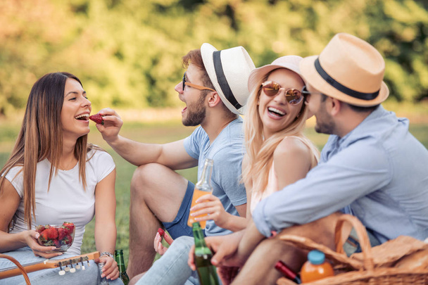 Счастливые друзья в парке на пикнике, едят клубнику
. - Фото, изображение