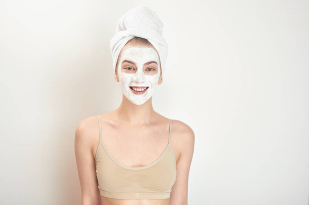 attractive woman with face mask and towel on head looking at camera isolated on white background, close-up  - Photo, Image