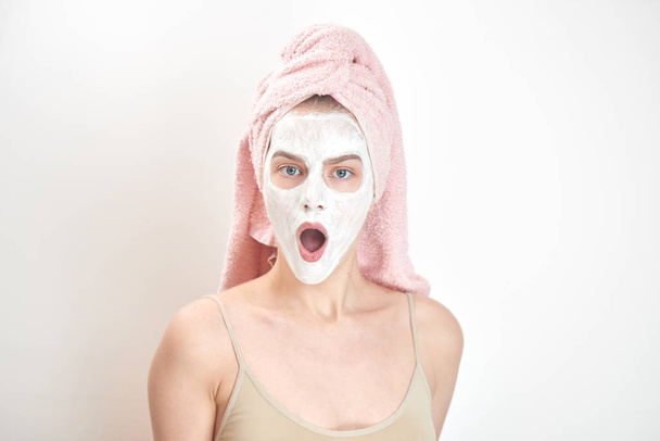 astonished woman with towel on head and mask on face looking at camera with opened mouth , beauty treatment concept  - Foto, immagini