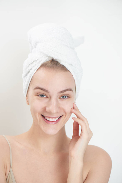 young woman with towel on head touching clean face skin, skin care concept - 写真・画像