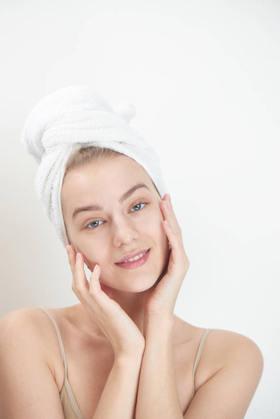 mujer joven con toalla en la cabeza tocando la piel limpia de la cara, concepto de cuidado de la piel
 - Foto, Imagen