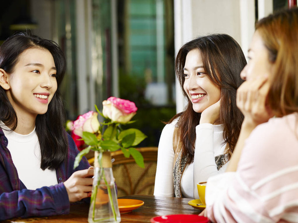 3 幸せな美しい若いアジア女性に座ってテーブルなコーヒー ショップや茶室の話をチャット. - 写真・画像